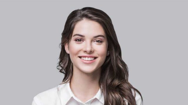Young woman smiling in front of grey background